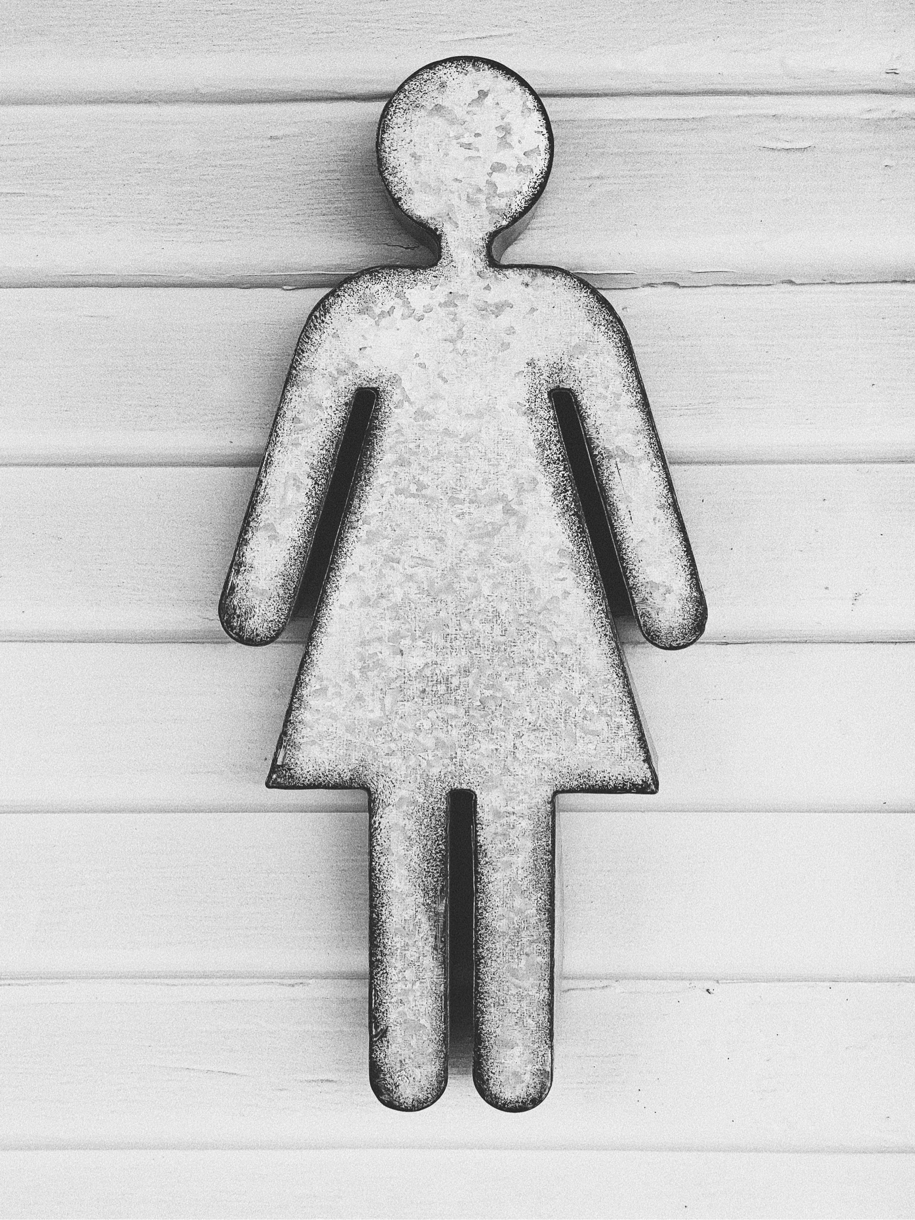 Shape of woman made out of metal affixed to wood siding