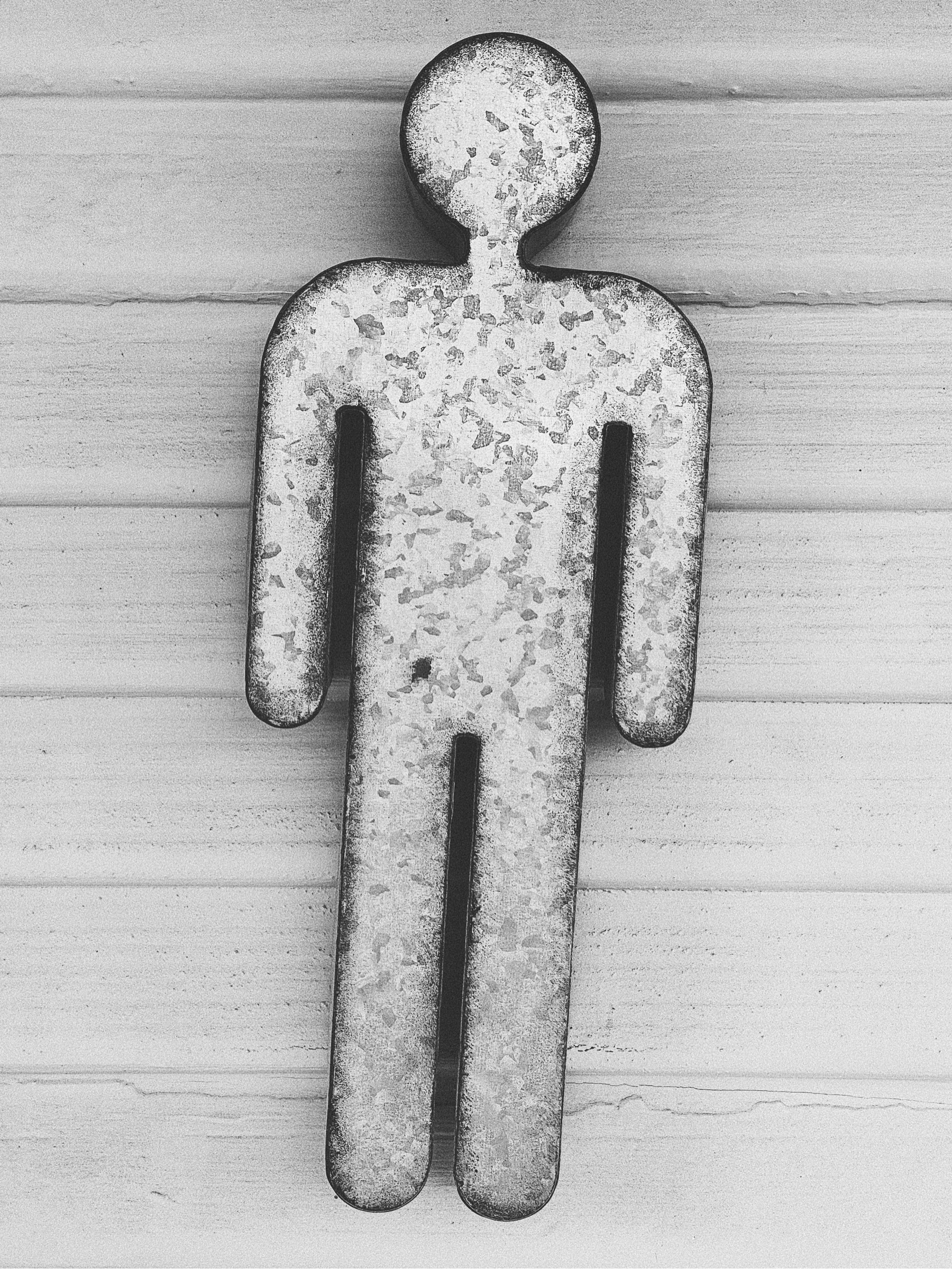 Shape of man made out of metal affixed to wood siding