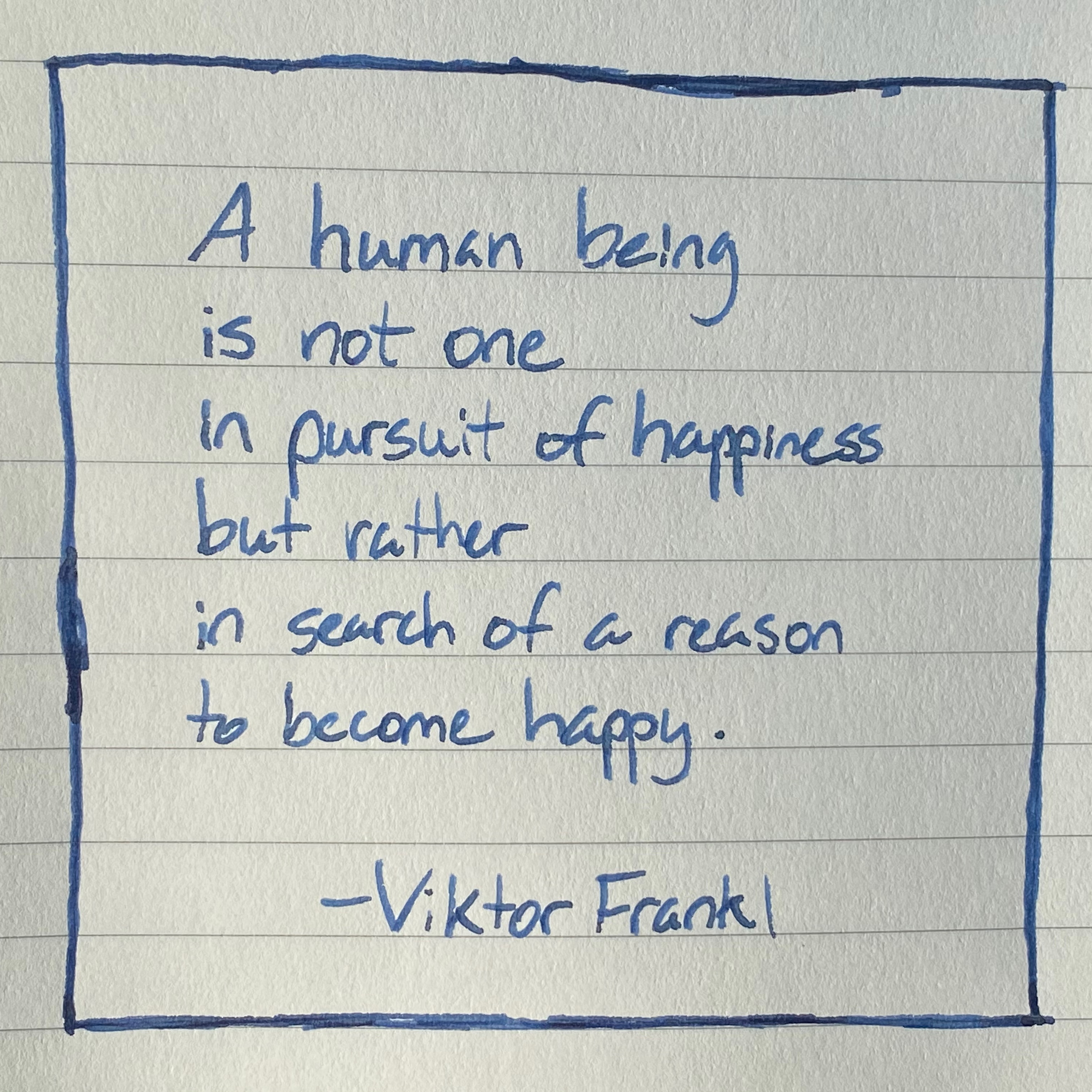 Handwritten quote in blue ink on lined paper with box around words by Viktor Frankl: A human being is not one in pursuit of happiness but rather in search of a reason to become happy.