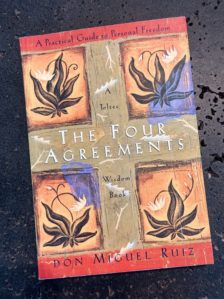 Front cover of the book 'The Four Agreements' laying on a black countertop