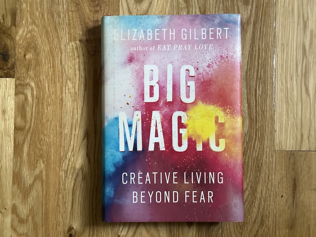 Front cover of the book 'Big Magic' laying on a wood floor
